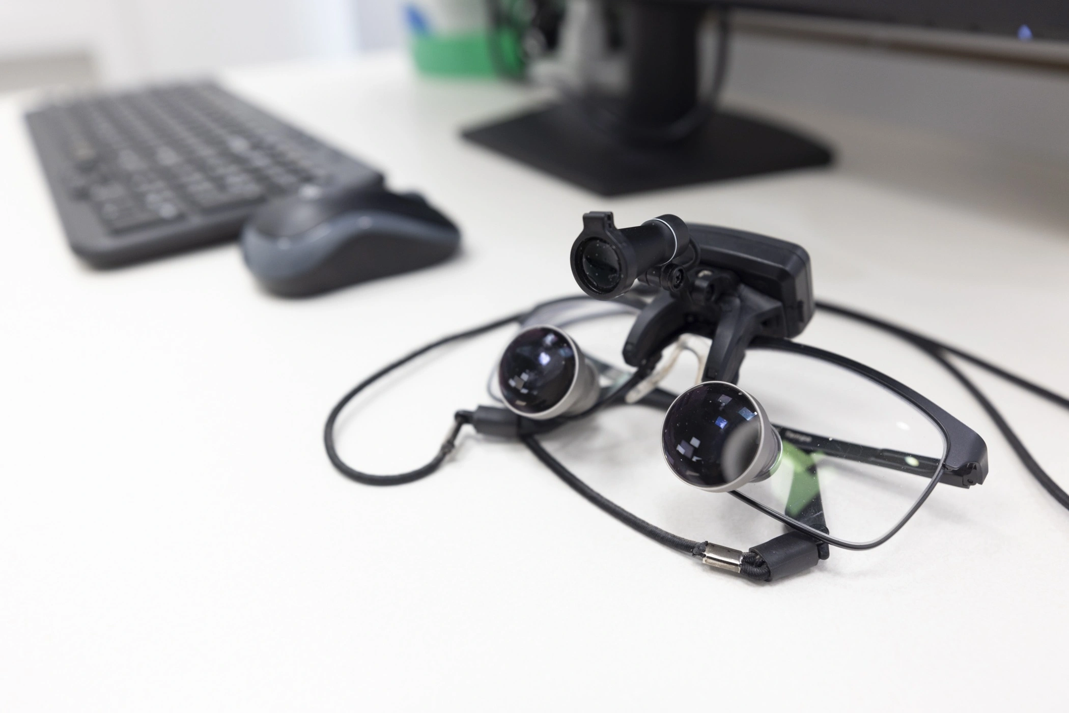 professional dental loupes magnifying glasses on a desk next to a computer keyboard and mouse